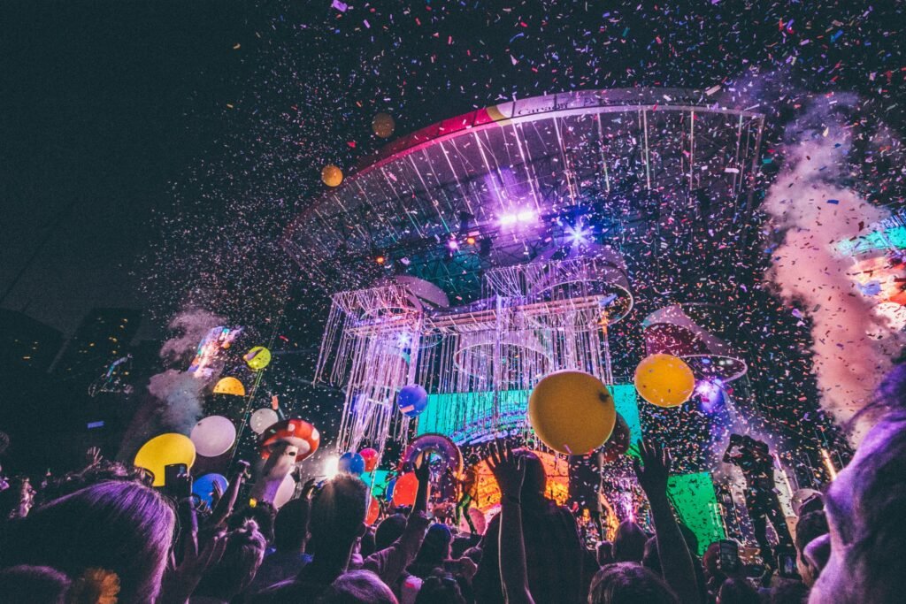 Exciting night concert with confetti, balloons, and a lively audience enjoying the vibrant atmosphere.
